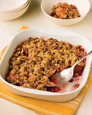 Martha Stewart apple-cranberry crumble in a white baking dish with a golden pecan oat topping and a spoon