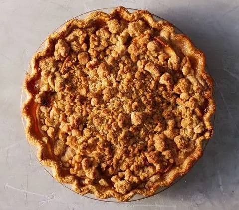 Martha Stewart apple crumble pie with a golden oat crumble topping and crimped crust in a glass pie dish