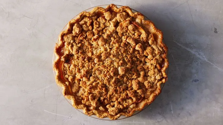 Martha Stewart apple crumble pie with a golden oat crumble topping and crimped crust in a glass pie dish
