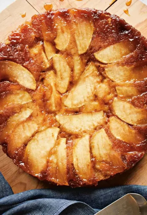 Martha Stewart apple-honey upside-down cake with glossy caramelized apple wedges on a wooden board with a cake server