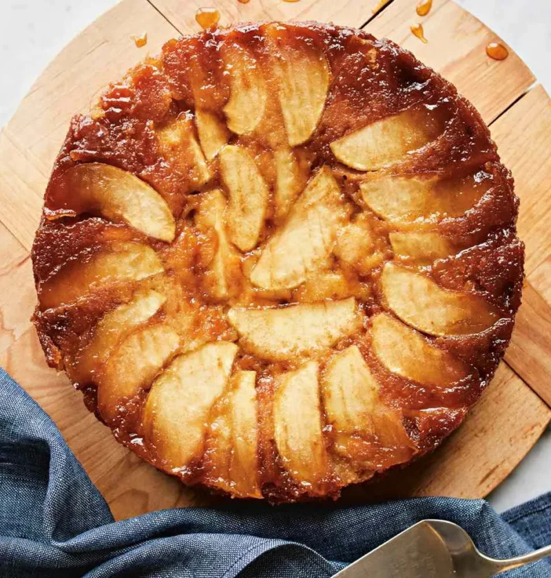 Martha Stewart apple-honey upside-down cake with glossy caramelized apple wedges on a wooden board with a cake server