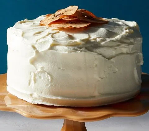 Martha Stewart apple layer cake with cream-cheese frosting on a scalloped cake stand, topped with apple chips