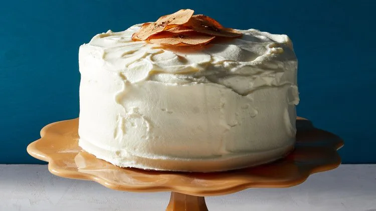 Martha Stewart apple layer cake with cream-cheese frosting on a scalloped cake stand, topped with apple chips