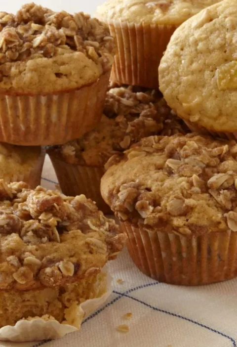 Martha Stewart apple-oatmeal muffins with oat crumb topping stacked on a blue striped kitchen towel