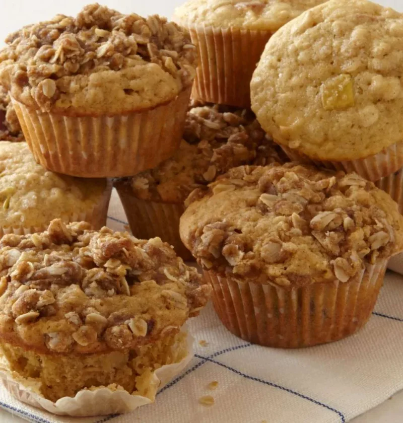 Martha Stewart apple-oatmeal muffins with oat crumb topping stacked on a blue striped kitchen towel