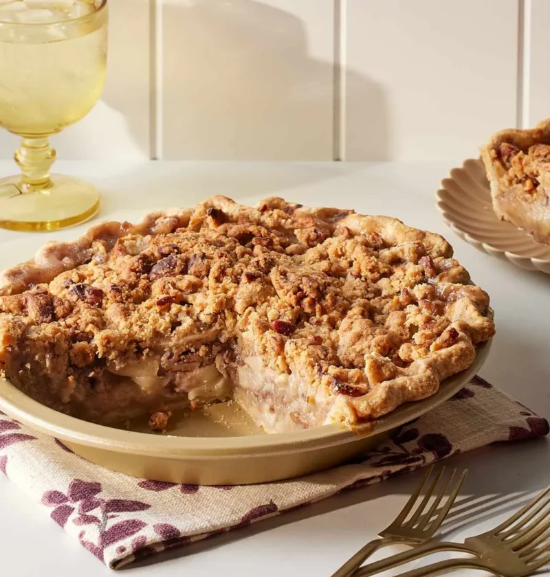 Martha Stewart apple pecan pie with crumb topping in a pie plate with a slice served on a plate beside it