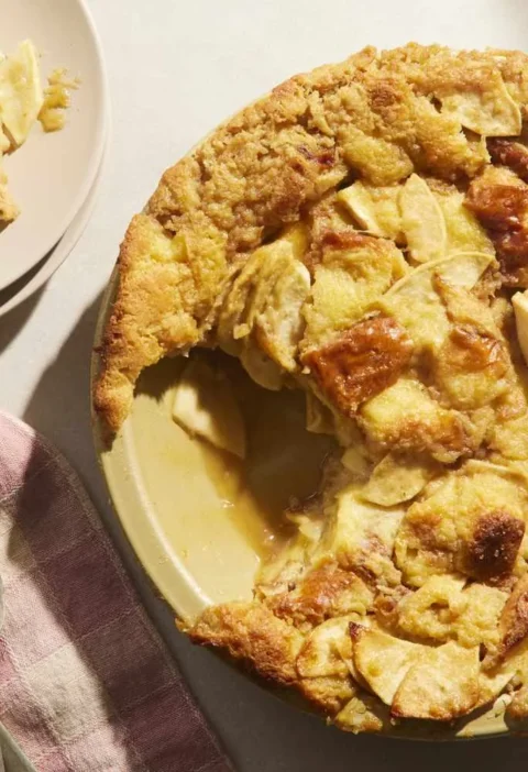 Martha Stewart apple pie bread pudding baked in a pie plate with a scoop of vanilla ice cream on a plate beside it