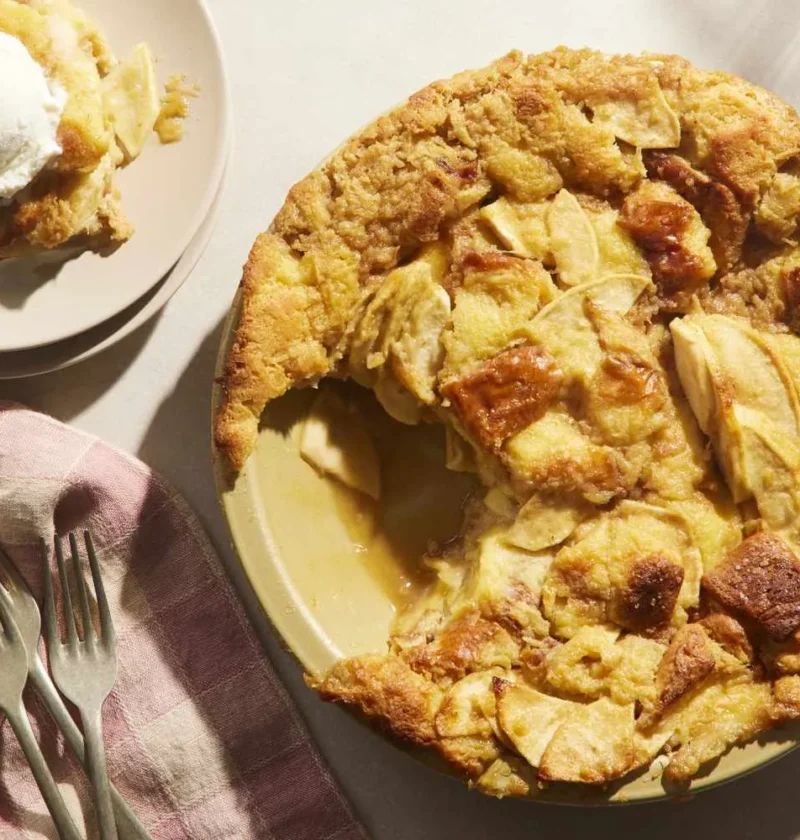 Martha Stewart apple pie bread pudding baked in a pie plate with a scoop of vanilla ice cream on a plate beside it