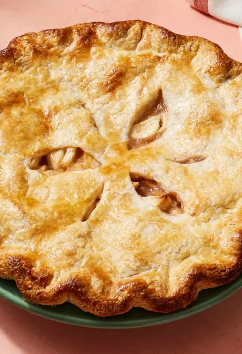 Martha Stewart apple pie crust recipe baked golden brown with a fluted edge and slits on a green pie plate