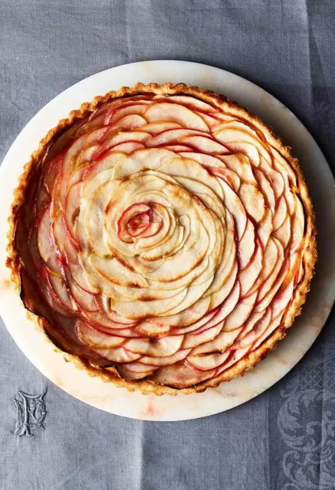 Martha Stewart apple rose tart with thin blushing apple slices arranged in a spiral rose on a white marble plate