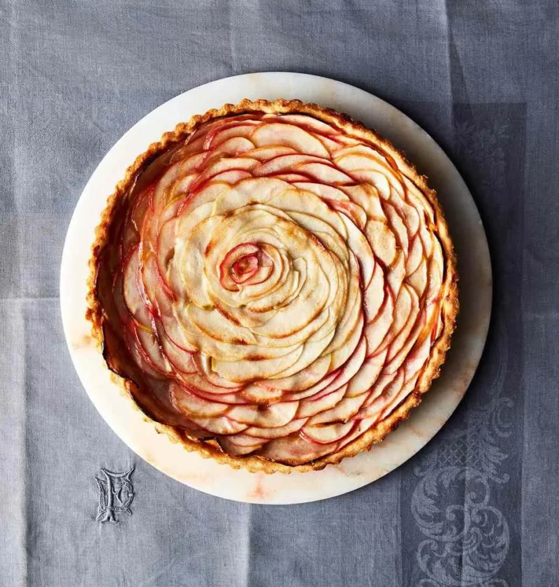 Martha Stewart apple rose tart with thin blushing apple slices arranged in a spiral rose on a white marble plate