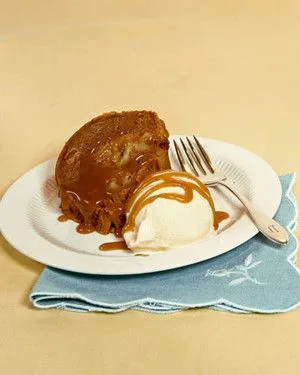 Slice of Martha Stewart apple spice cake drizzled with caramel sauce next to a scoop of vanilla ice cream on a white plate
