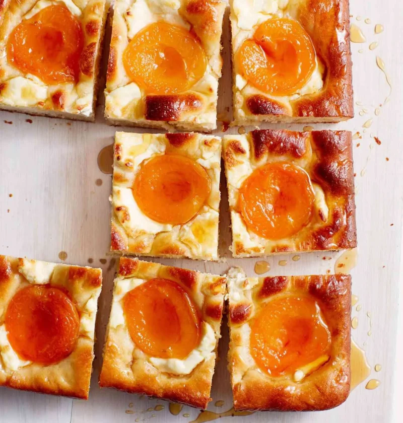 Martha Stewart apricot-and-cream cheese squares with golden crust, apricot halves and honey drizzle on a wooden board