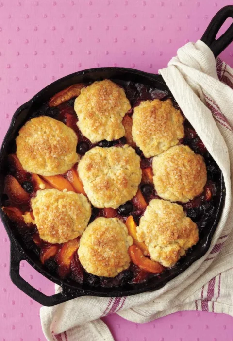 Martha Stewart apricot-blueberry cobbler with golden biscuit mounds over apricot wedges and blueberries in a cast-iron skillet