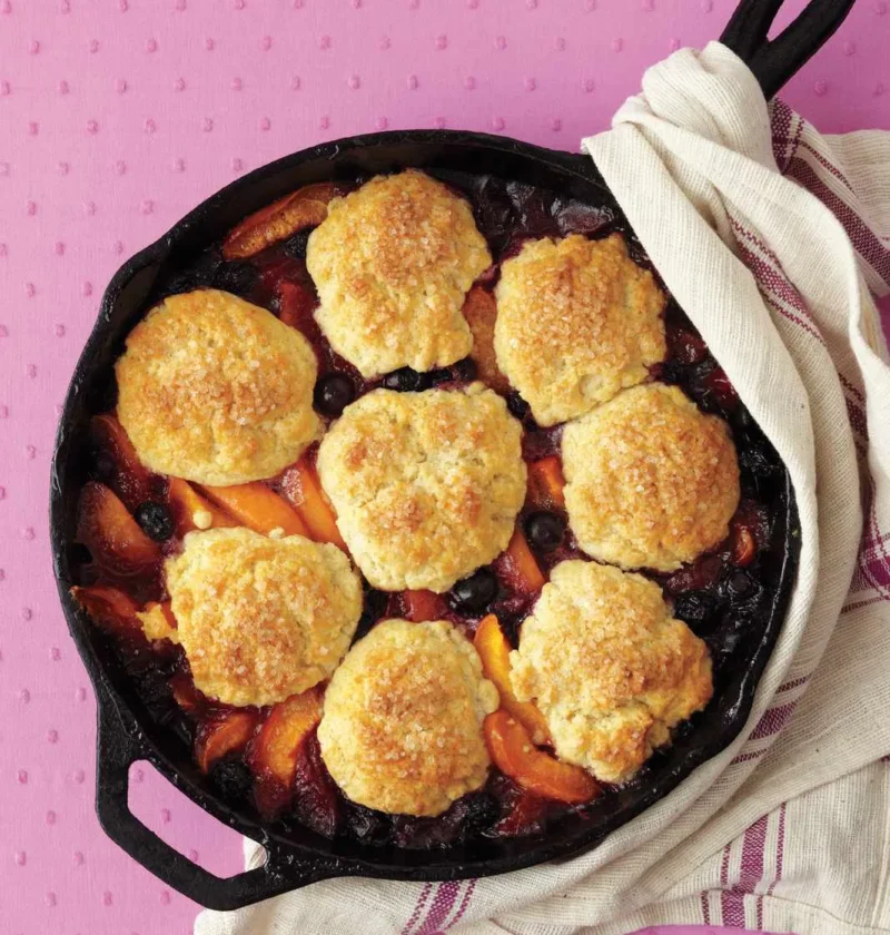 Martha Stewart apricot-blueberry cobbler with golden biscuit mounds over apricot wedges and blueberries in a cast-iron skillet