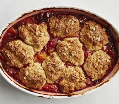 Martha Stewart apricot cobbler in an oval baking dish with golden oat-topped biscuits over bubbling red fruit
