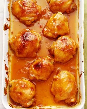 Martha Stewart apricot-Dijon-glazed chicken thighs baked in a white dish with a sticky orange glaze and pan sauce