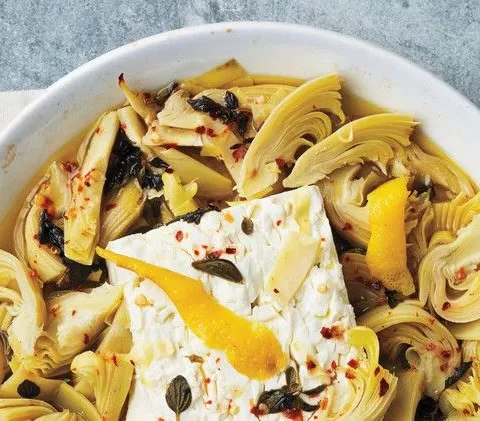 Martha Stewart artichoke-and-feta dip with a baked feta block, artichoke hearts, lemon zest and oregano in a white pie dish