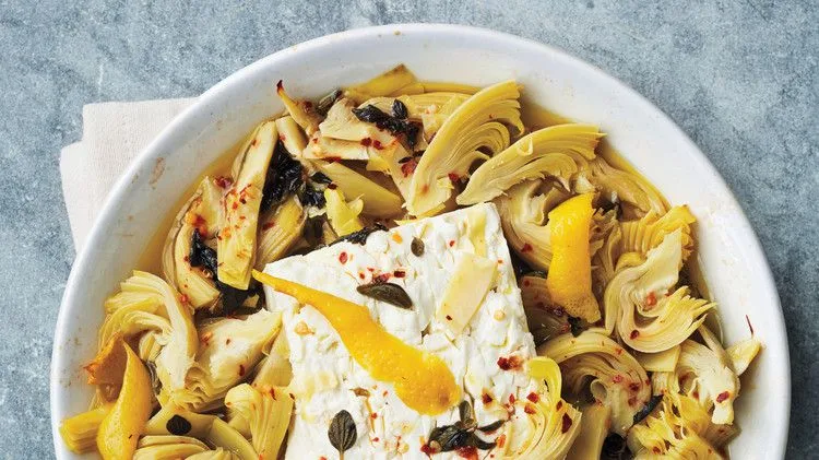 Martha Stewart artichoke-and-feta dip with a baked feta block, artichoke hearts, lemon zest and oregano in a white pie dish