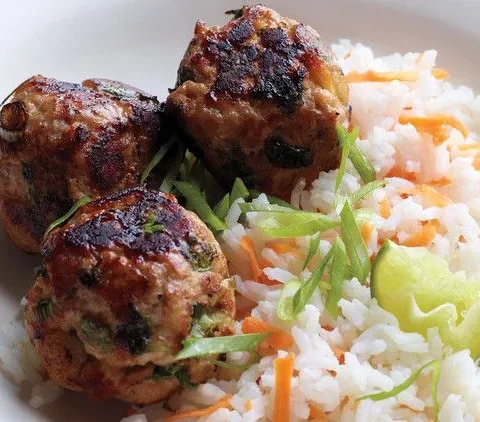 Martha Stewart Asian turkey meatballs with carrot rice, scallions and a lime wedge on a white plate