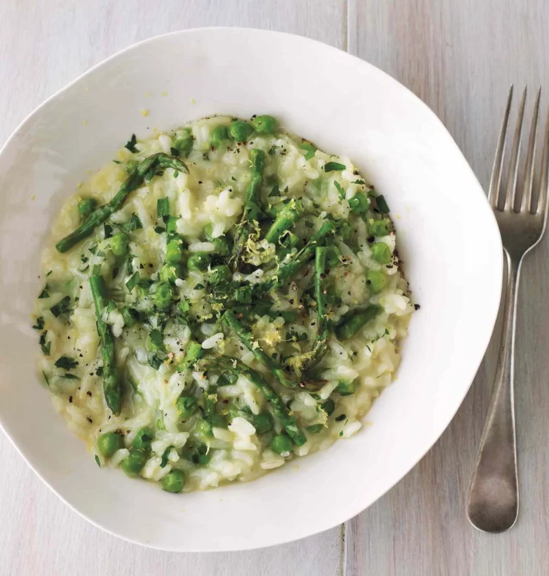 Martha Stewart asparagus-and-lemon risotto with green peas, asparagus pieces and lemon zest in a white bowl beside a fork