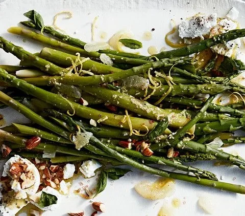 Martha Stewart asparagus with almonds, goat cheese, and basil on a white platter drizzled with lemon dressing