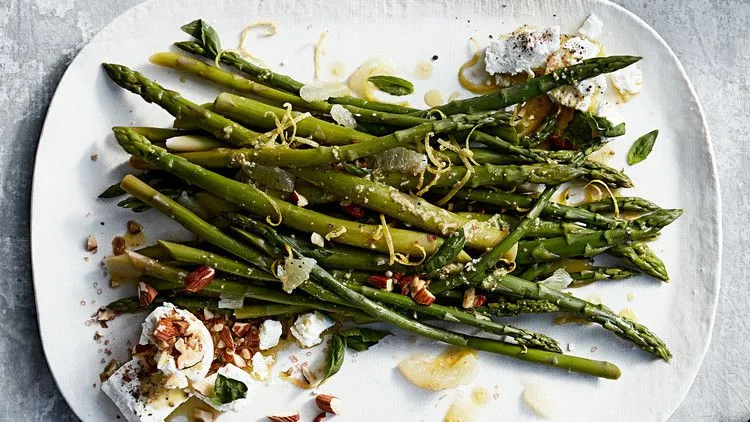 Martha Stewart asparagus with almonds, goat cheese, and basil on a white platter drizzled with lemon dressing
