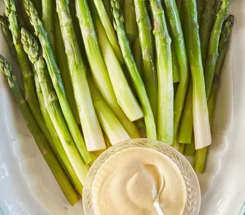 Martha Stewart asparagus with blender hollandaise, green spears on a white platter with a glass bowl of creamy yellow sauce