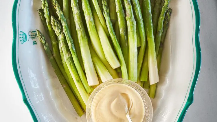 Martha Stewart asparagus with blender hollandaise, green spears on a white platter with a glass bowl of creamy yellow sauce