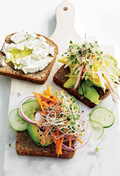 Martha Stewart avocado-and-sprout club sandwiches on whole-grain toast with goat cheese, avocado, sprouts, carrots, cucumber and red onion on a marble board