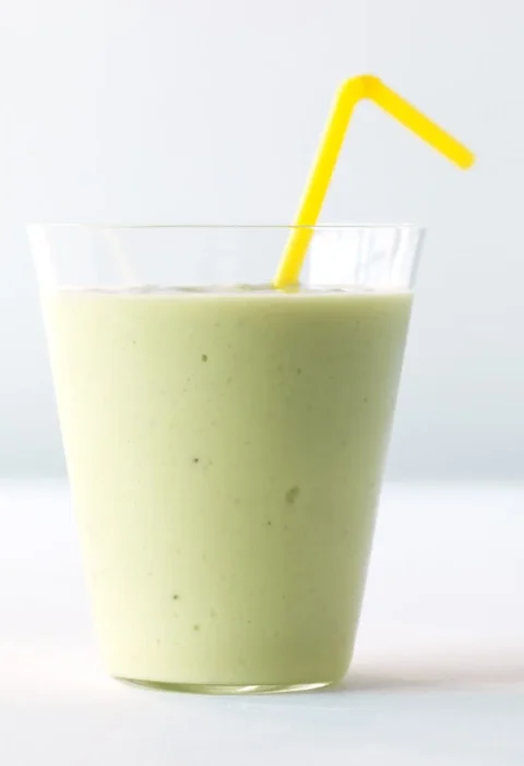 Martha Stewart avocado-banana smoothie in a clear glass with a yellow bendy straw