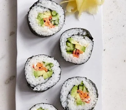 Martha Stewart avocado sushi rolls cut into pieces showing avocado, cucumber and carrot inside white rice and nori, served with pickled ginger