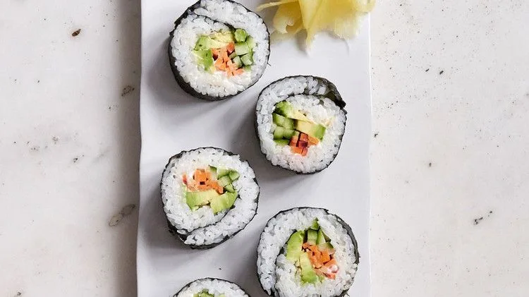 Martha Stewart avocado sushi rolls cut into pieces showing avocado, cucumber and carrot inside white rice and nori, served with pickled ginger