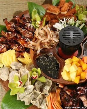 Martha Stewart baby pork ribs glazed with sesame seeds on a pupu platter with dumplings, pineapple and fresh fruit