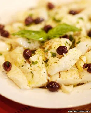 Martha Stewart baccala salad with flaked salt cod, Gaeta olives and fresh basil leaves on a white plate