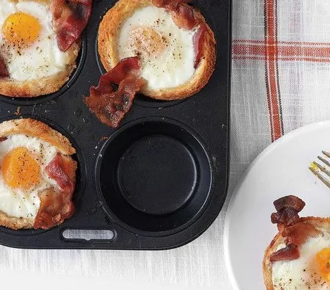 Martha Stewart bacon, egg and toast cups in a muffin tin with bacon slices and baked eggs, plus one served on a white plate with a fork