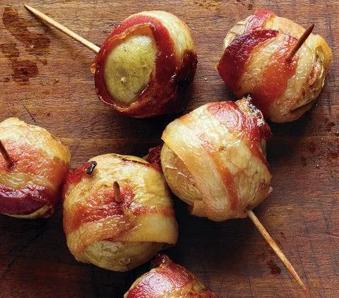 Martha Stewart bacon-wrapped potatoes secured with toothpicks on a wooden board