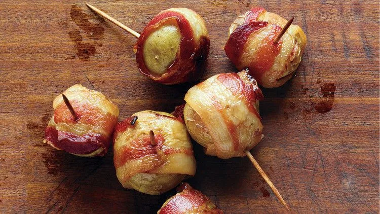 Martha Stewart bacon-wrapped potatoes secured with toothpicks on a wooden board