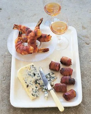 Martha Stewart bacon wrapped shrimp and dates served on a white platter with blue cheese and two glasses of white wine