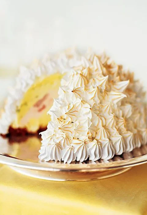 Martha Stewart baked Alaska with toasted Swiss meringue peaks and a slice cut away showing pistachio and cherry ice cream over chocolate cake