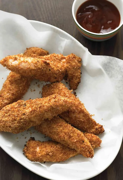 Martha Stewart baked chicken fingers with a golden bran and wheat germ crust on a white platter with barbecue sauce