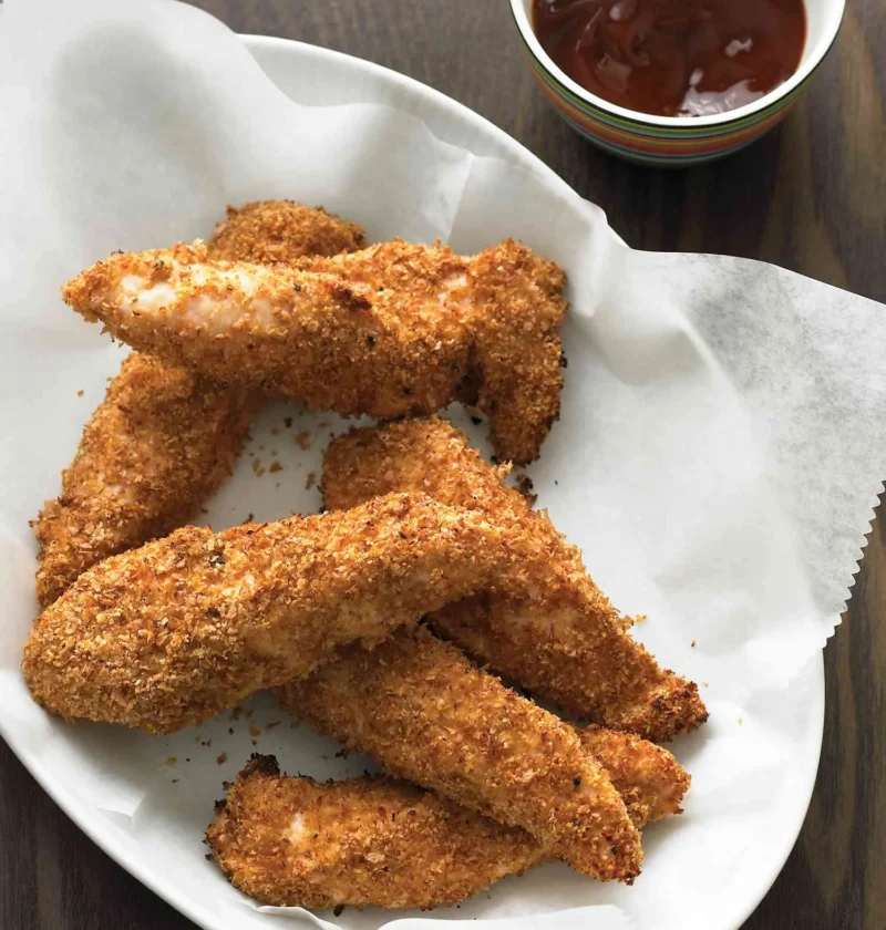 Martha Stewart baked chicken fingers with a golden bran and wheat germ crust on a white platter with barbecue sauce