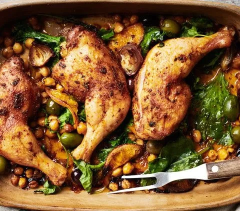 Martha Stewart baked chicken legs with chickpeas, olives and greens in a rustic baking dish with a serving fork