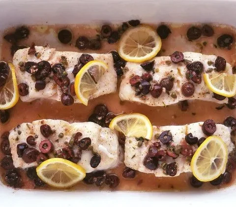 Martha Stewart baked cod with olives, with four cod fillets topped with chopped Kalamata olives, capers and lemon slices in a white baking dish