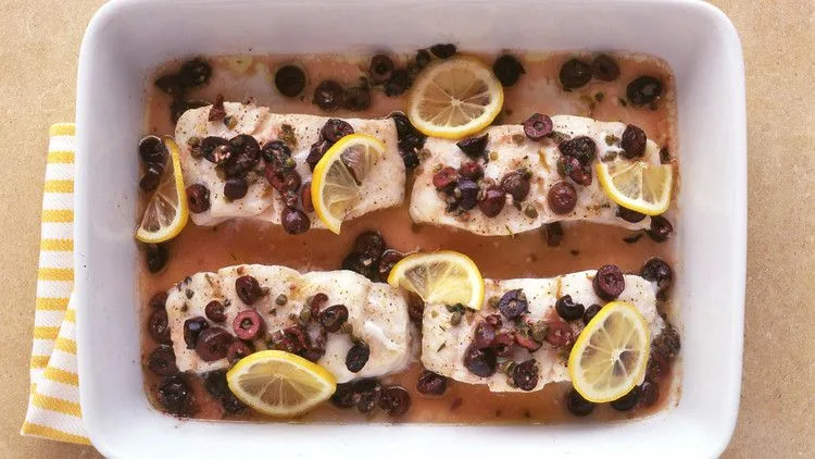 Martha Stewart baked cod with olives, with four cod fillets topped with chopped Kalamata olives, capers and lemon slices in a white baking dish