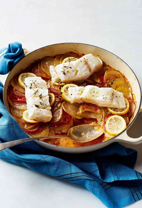 Martha Stewart baked cod with tomatoes and potatoes in a cream Dutch oven topped with lemon slices and thyme