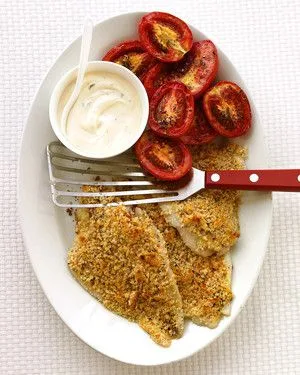 Martha Stewart baked flounder with roasted tomatoes, showing golden bread-crumb fillets, roasted plum tomato halves and a bowl of creamy sauce on an oval platter