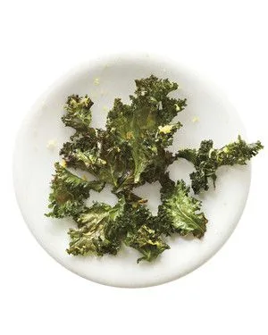 Martha Stewart baked kale chips, crisp torn kale leaves with lemon zest on a white plate