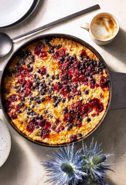 Martha Stewart baked oatmeal for a crowd with berries and seeds in a black baking dish with pepitas on the side