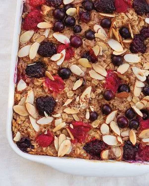 Martha Stewart baked oatmeal topped with sliced almonds, blueberries and raspberries in a white baking dish